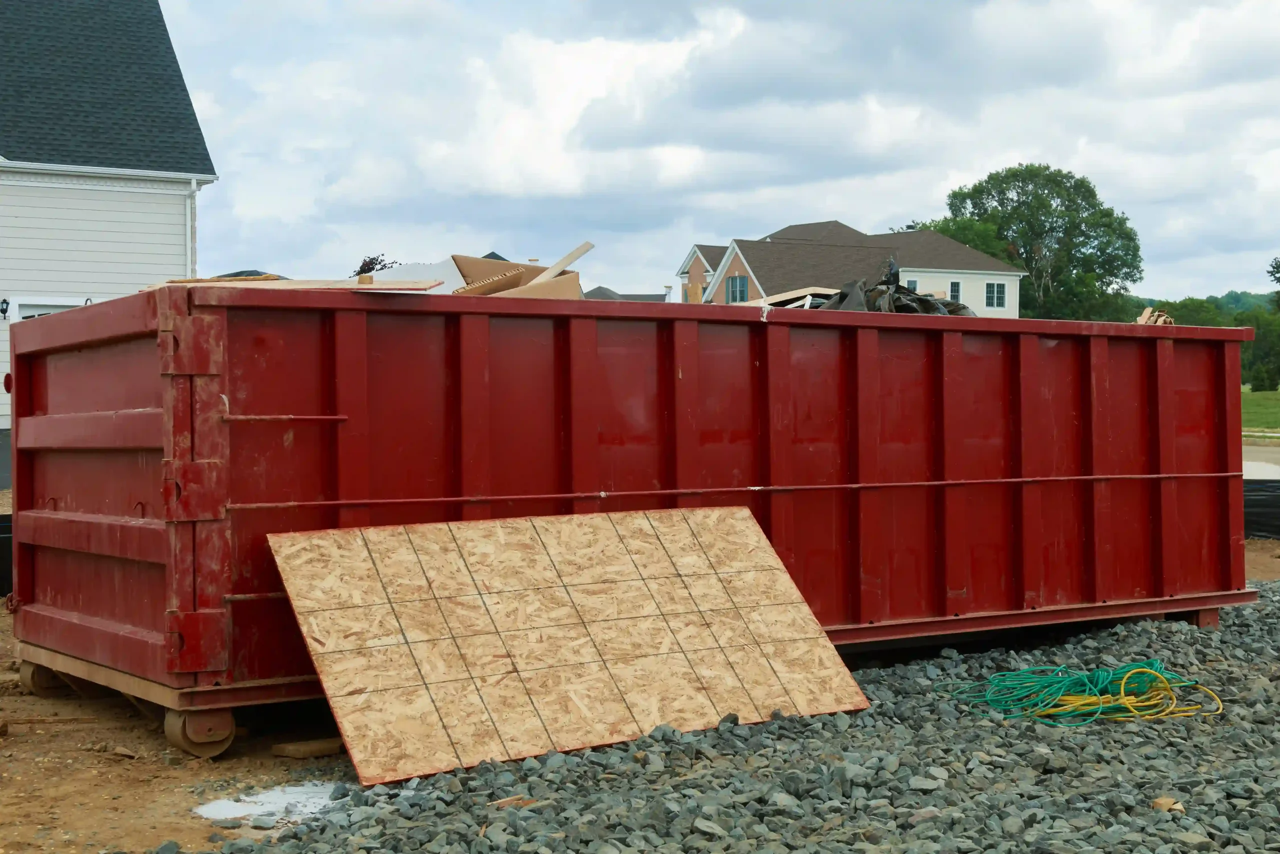 Großer roter Container vor einem Haus für die Entsorgung von Gegenständen bei einer Entrümpelung. Symbolisiert die professionelle Entrümpelung und Entsorgung.