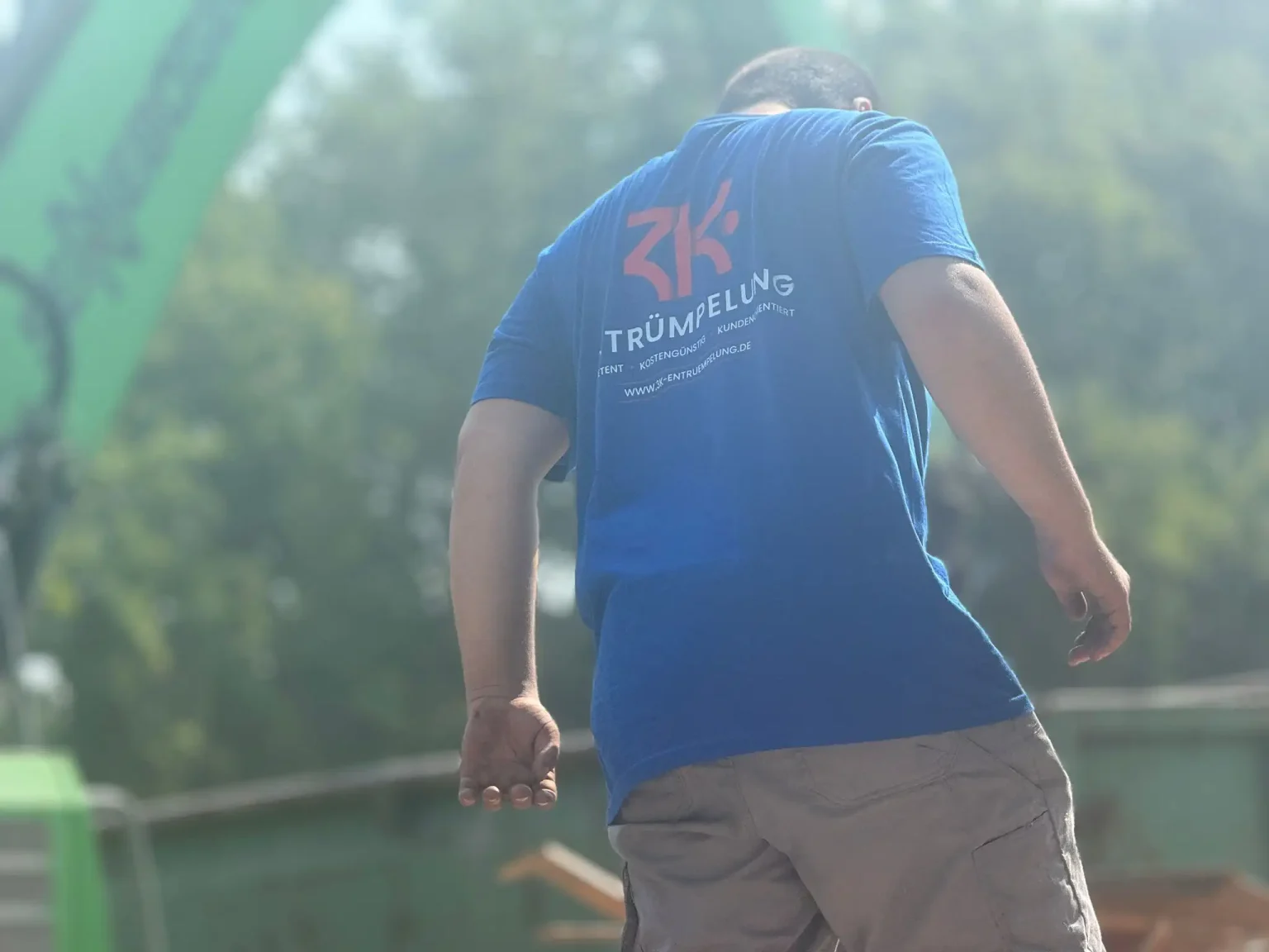 Ein Mitarbeiter unseres Entrümpelungsunternehmens in einem blauen T-Shirt mit Firmenlogo, bei der Arbeit im Freien.